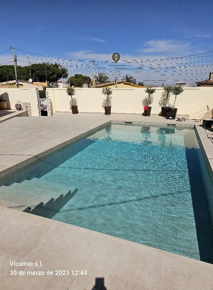 Piscina reformada con porcelánico en tono arena y albardilla efecto piedra